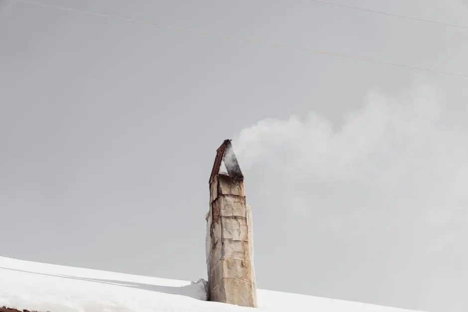 A solitary smokestack releases smoke into the clear winter sky in snowy Mudurnu, Türkiye.
